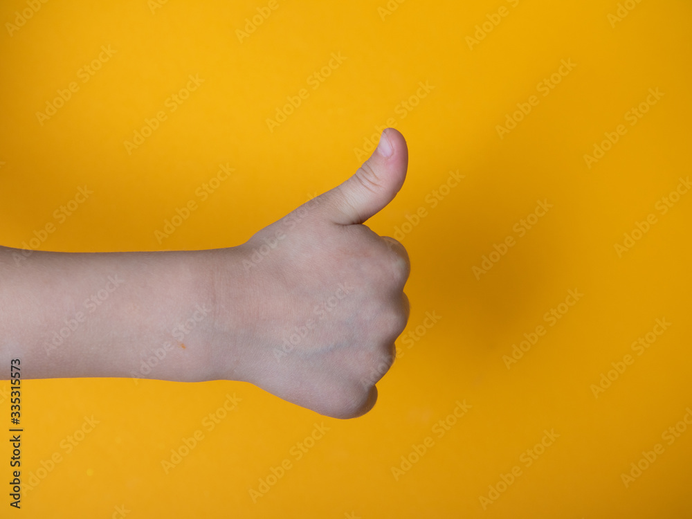 child thumb up isolated with yellow background
