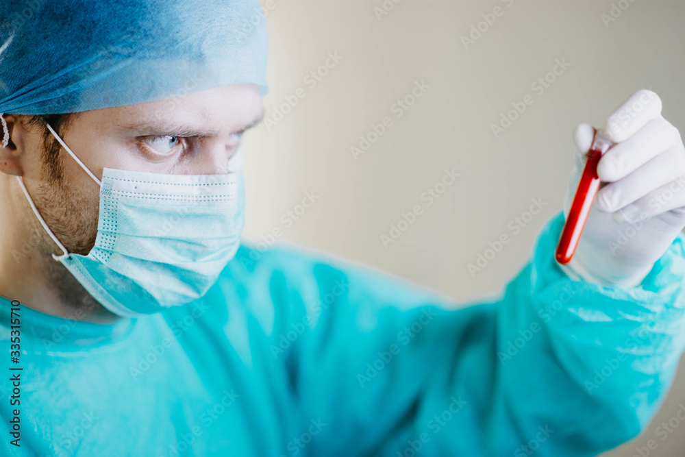 doctor in uniform examines a blood test in a medical test tube in a laboratory. doctor in uniform examines a blood test in a medical test tube in a laboratory.