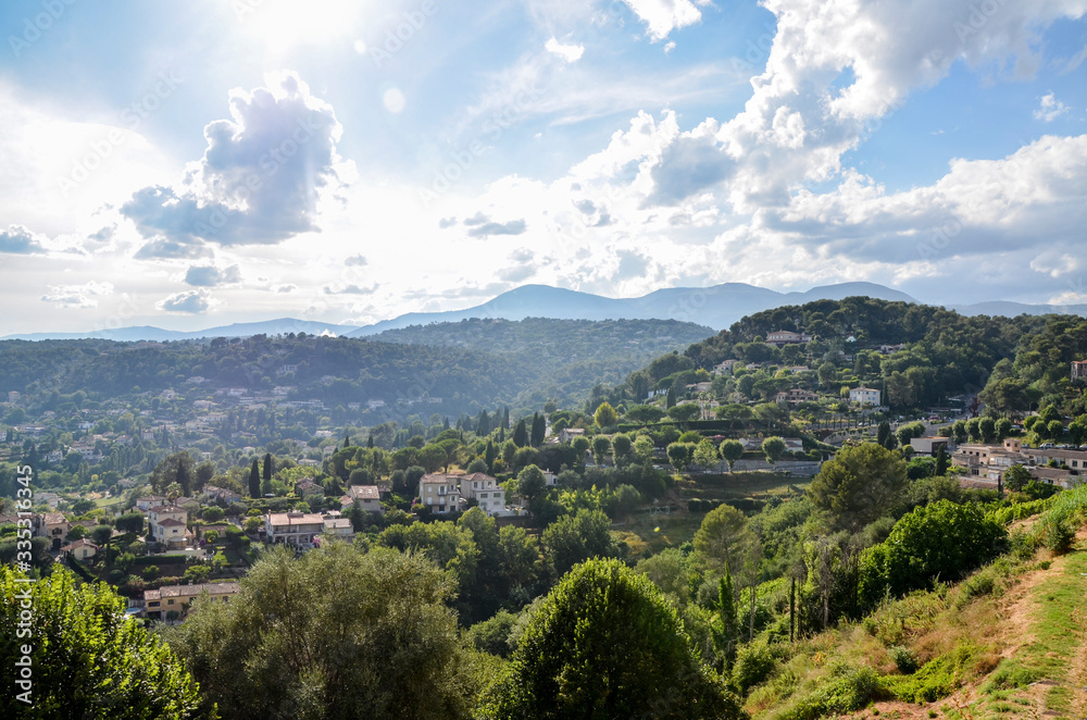 Panoramic rural landscape small houses on a hill near the ancient French village Saint-Paul-de-Vence with the Maritime Alps mountains in the distance, Provence, France at sunny summer day
