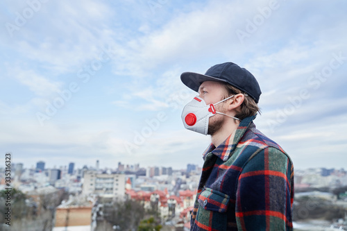 City view portrait of a man in protective medical mask. Closeup of a attractive young male in a respirator to protect against virus infection or with smog