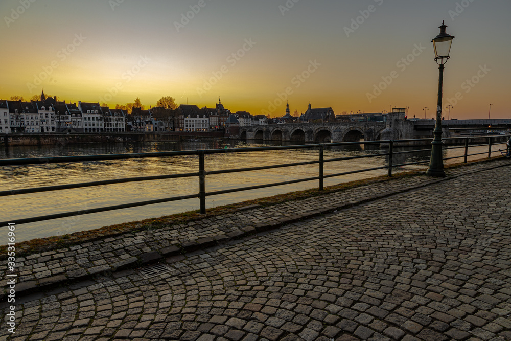 View on the skyline of Maastricht during sunset seen from the Wyck neighbourhoud with a view on the typical cobbelstone streets, river Meuse and the old roman bridge