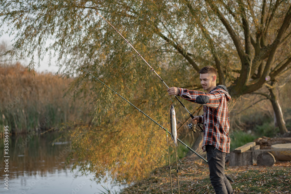 Man by the river. Guy in a red shirt. Man in a fishing.