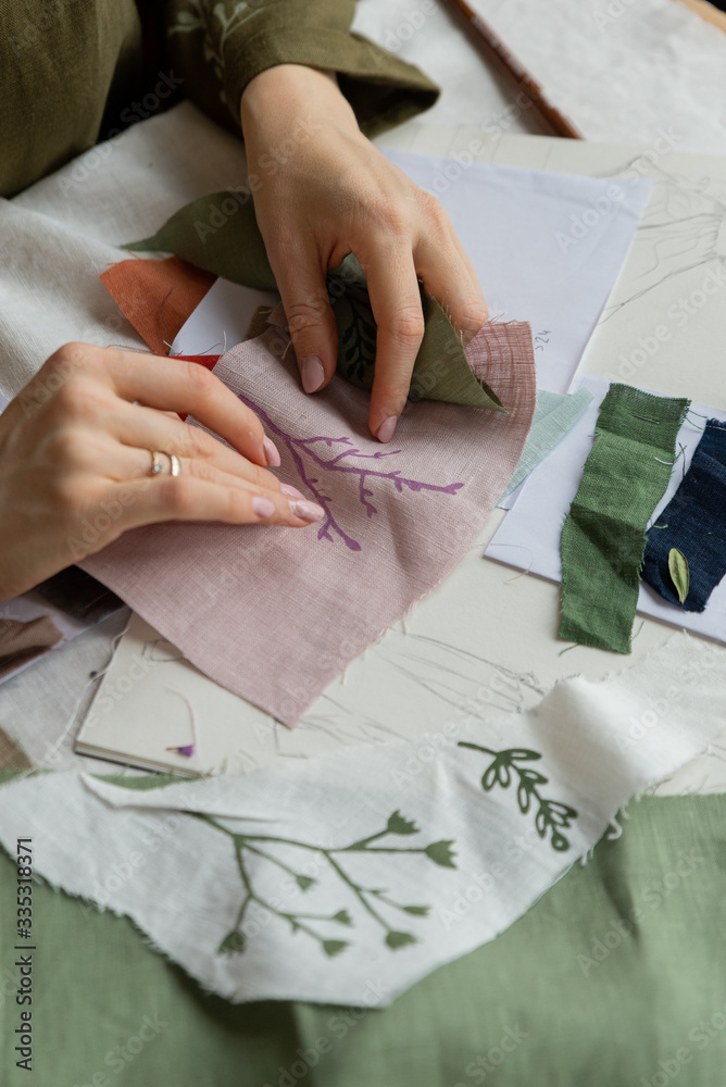 Dressmaker hands holding linen clothes with drawing flora print. Dressmaker hands holding linen clothes with drawing flora print.