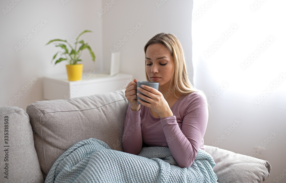 Sick woman sitting under the blanket drinking tea. Sick woman with seasonal infections, flu, allergy lying in bed. Sick woman covered with a blanket lying in bed with high fever and a flu, resting. Sick woman sitting under the blanket drinking tea. Sick woman with seasonal infections, flu, allergy lying in bed. Sick woman covered with a blanket lying in bed with high fever and a flu, resting.