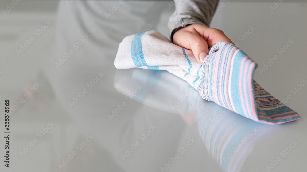 Fototapeta premium Cleaning wipe with a cloth in the hands of woman kitchen table. Housekeeping service. The concept of disinfection. Protection from viruses and bacteria