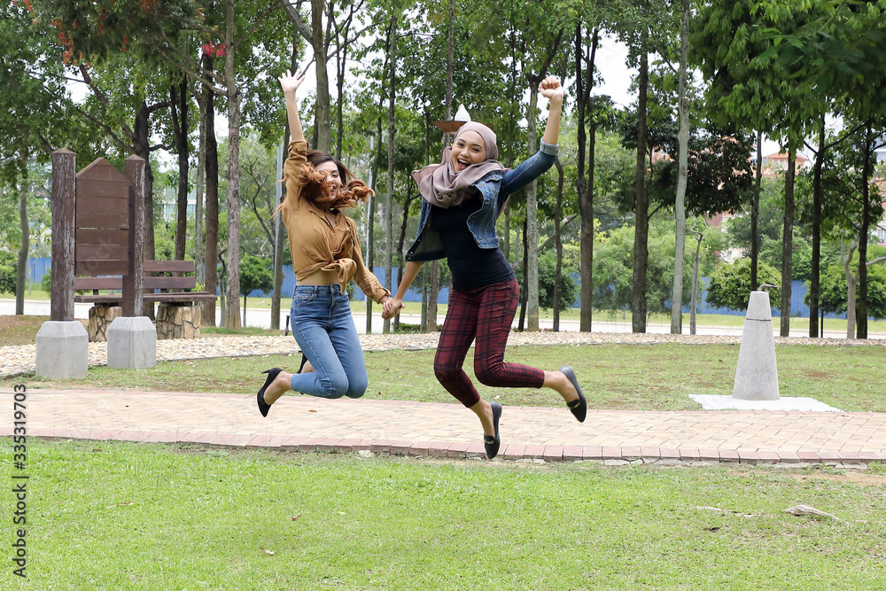 Obraz premium Young Asian Malay man woman outdoor green park joy happy jump in the air