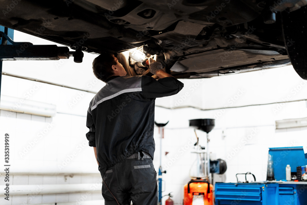 a man repairs a car raised on a lift a man repairs a car raised on a lift