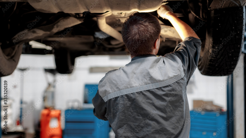 a man repairs a car raised on a lift