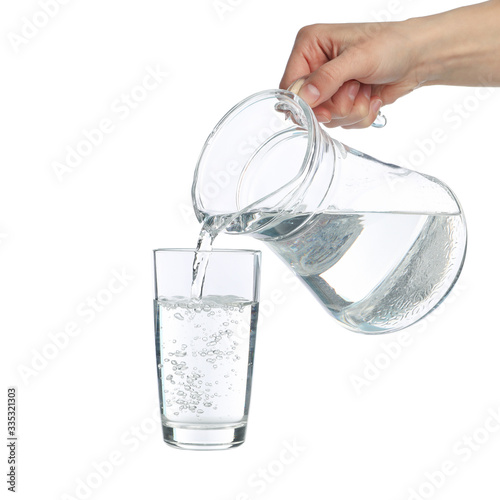 Pouring purified fresh water from the jug in glass, isolated on white background