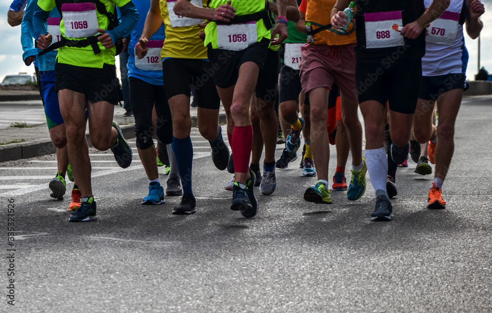 Group of active people running,marathon runners on the city road, detail of legs. Group of active people running,marathon runners on the city road, detail of legs.