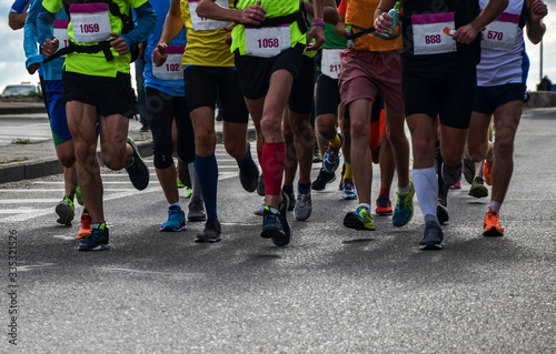 Group of active people running,marathon runners on the city road, detail of legs.