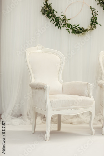 Elegant light-blue arm-chair and tender flowers near white wall. Interior in white colors. chair with luxurious upholstery in plain white interior