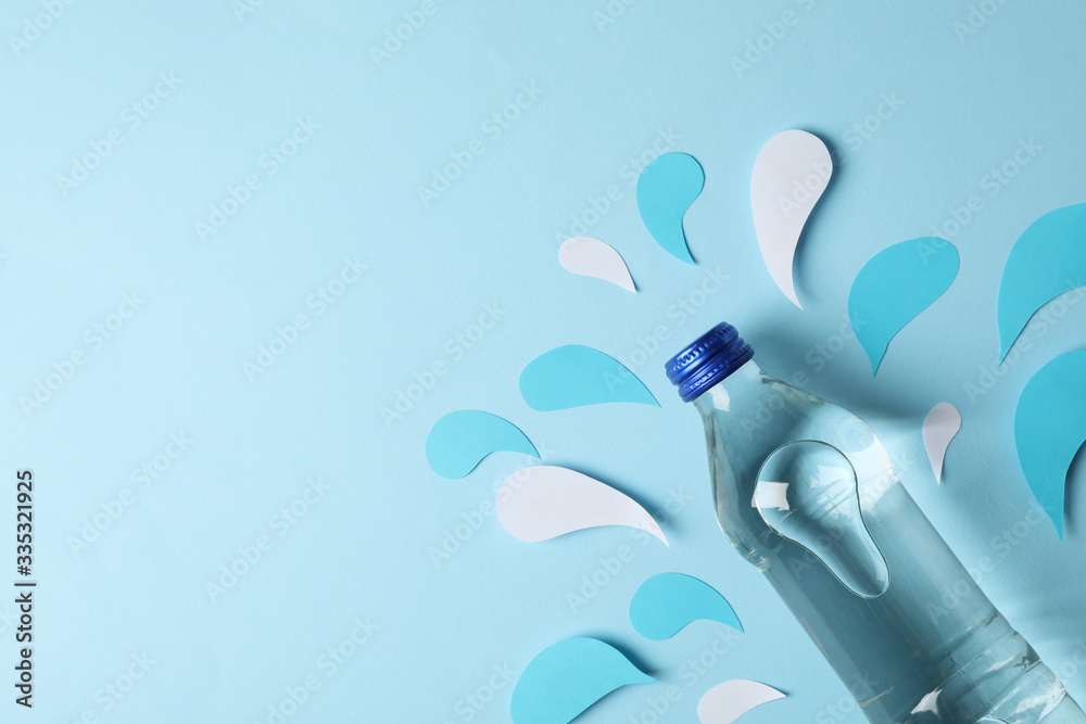 Bottle with water on decorative blue background, top view