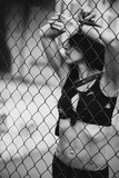 beautiful athletic woman in black clothes on the playground behind bars. Quarantine, self-isolation. Healthy lifestyle. Soft selective focus.