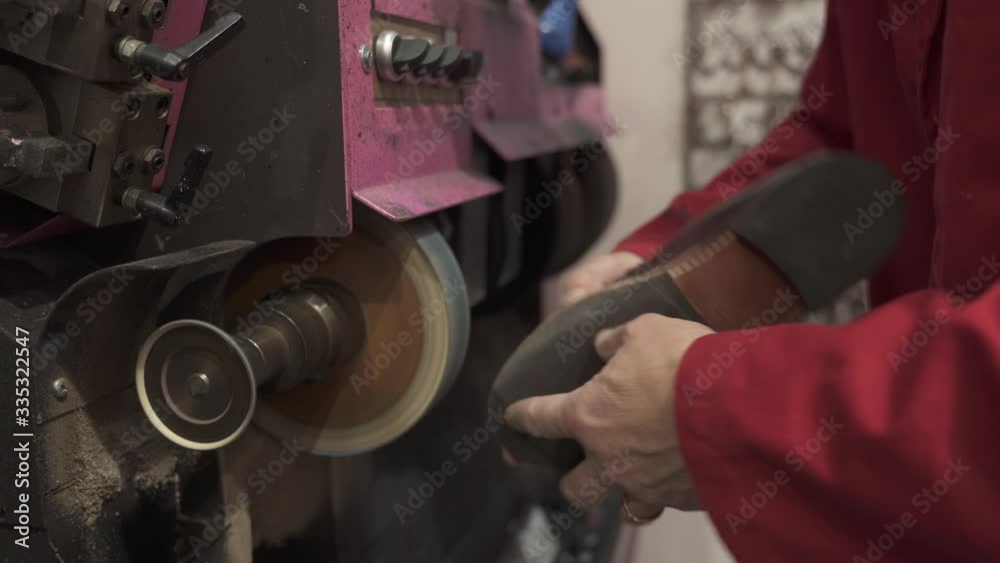 Shoemaker polishing the sole of a shoe with a disc on an electric machine Shoemaker polishing the sole of a shoe with a disc on an electric machine