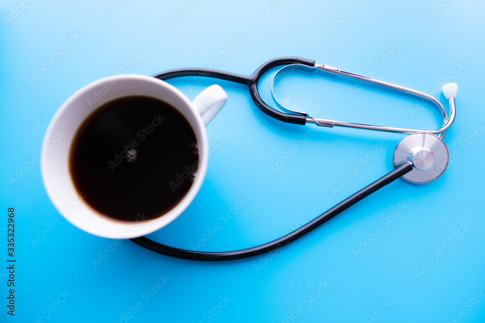 coffee cup and stethoscope, relaxing concept for doctor. On a blue background. Medical background concept coffee cup and stethoscope, relaxing concept for doctor. On a blue background. Medical background concept