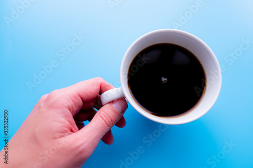Cups of black tea in the hands of men on a blue background. with copy space. top view