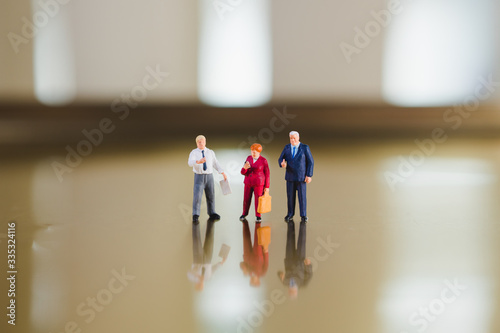Miniature elderly man and woman standing together using as business teamwork concept photo