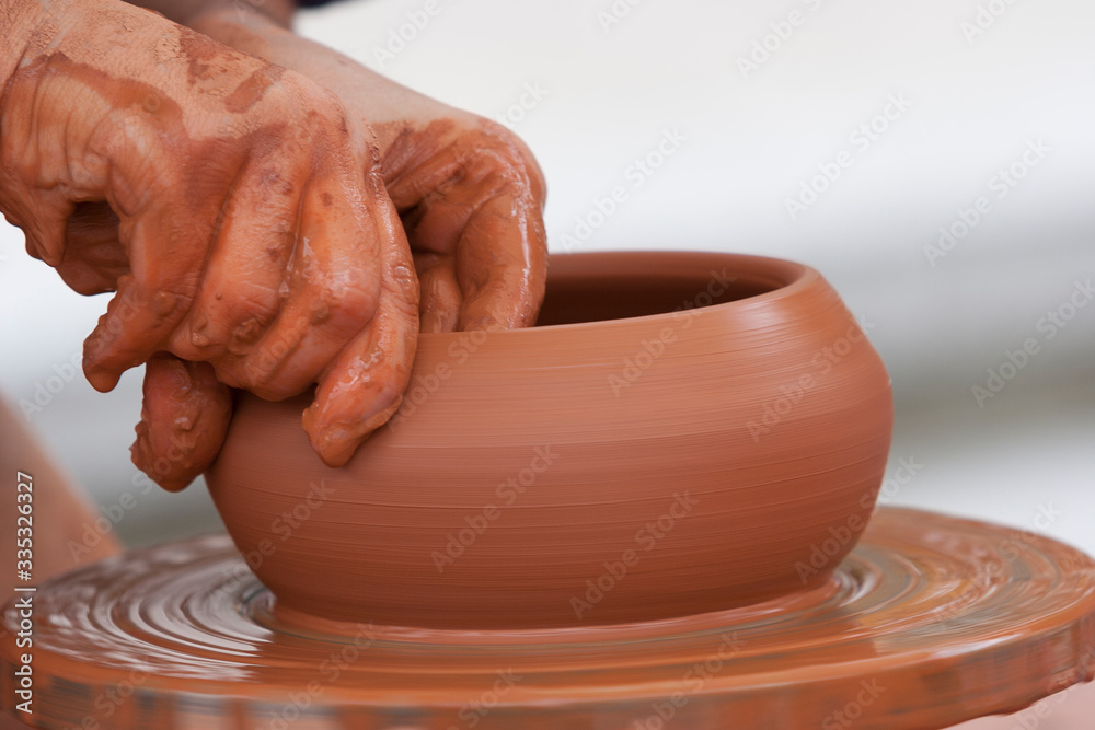 hands shaping a ceramic pot on spinning pottery wheel