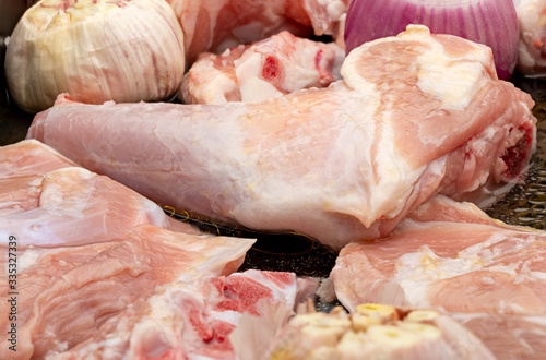 Raw meat of suckling lamb (suckling lamb). Prepared on a roasting tray (with garlic and red onion). photo