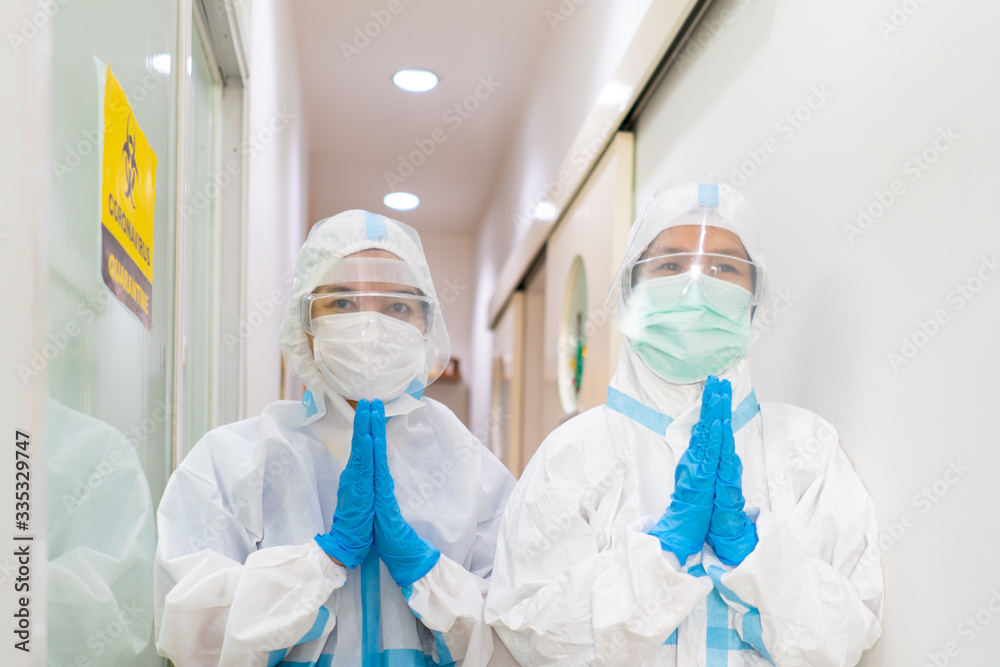 Two doctors in personal protective equipments are paying respect by pressing the hands togather at the chest in the hospital. covid-19, coronavirus, social distancing, isolation, medical concept Two doctors in personal protective equipments are paying respect by pressing the hands togather at the chest in the hospital. covid-19, coronavirus, social distancing, isolation, medical concept