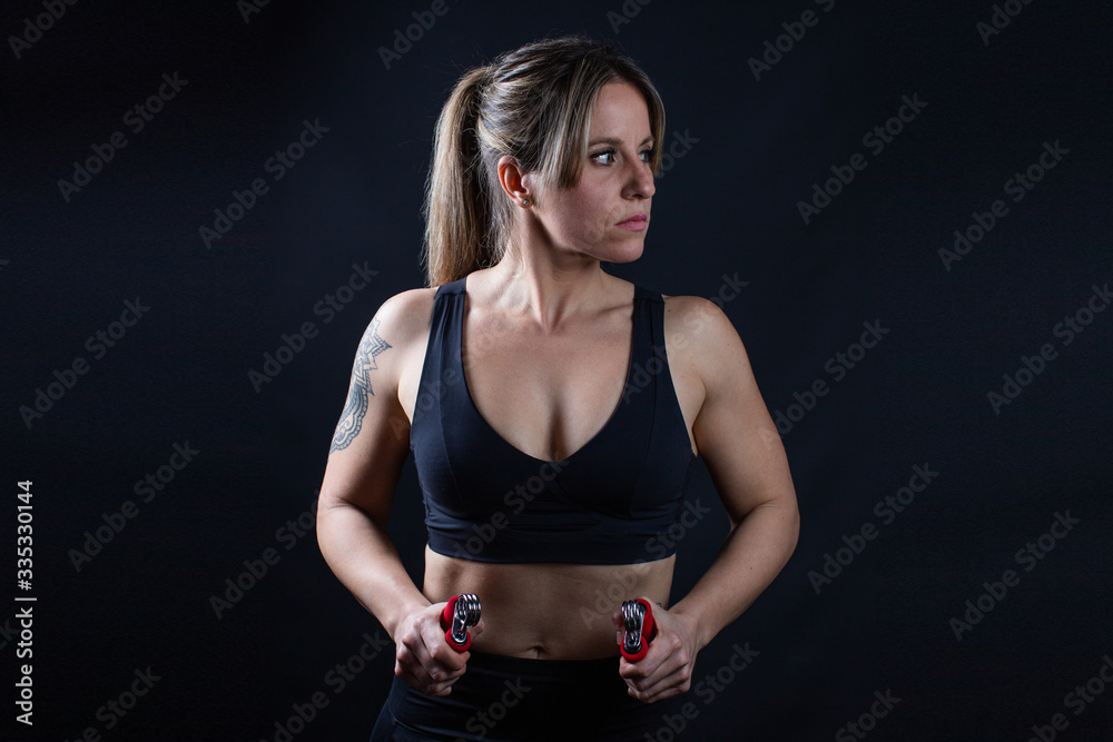Obraz premium Fitness athlete woman with black clothes and red grips, black background, sports