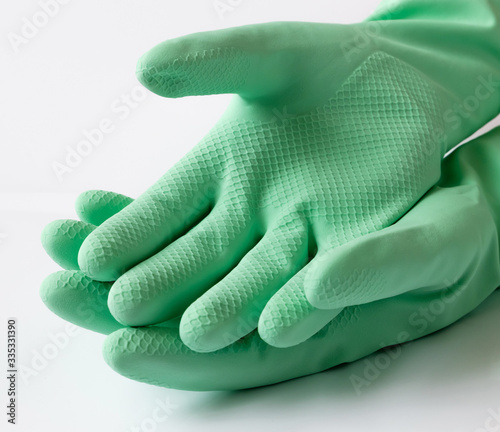 Hand in green latex dishwashing gloves on a white background photo