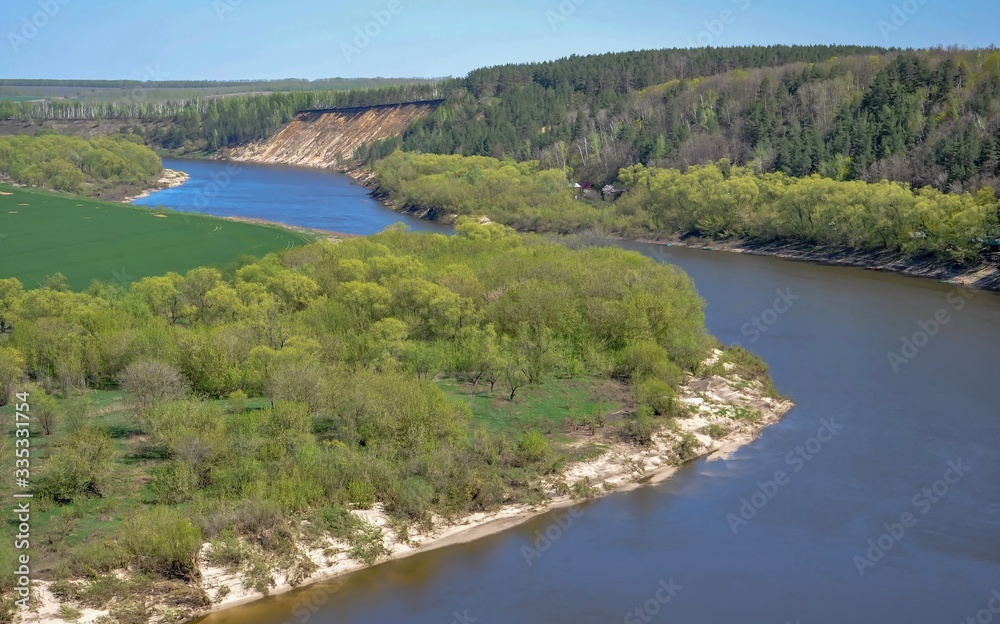 Panoramic top view of the bend of alarge river.Trees covered with fresh spring foliage grow along the banks