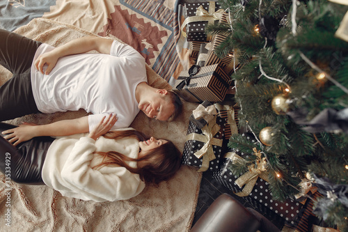Couple near christmas tree. Lady in a white sweater. Family sitting on a floor.