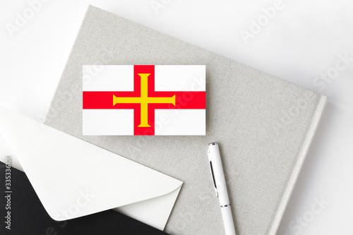 Guernsey flag on minimalist letter background. National invitation envelope with white pen and notebook. Communication concept. photo