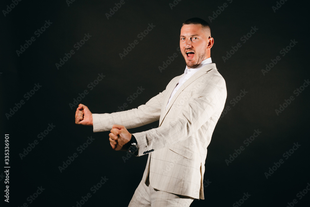 Business man in white suit is happy, celebrating a success on black bakground. Business man in white suit is happy, celebrating a success on black bakground.