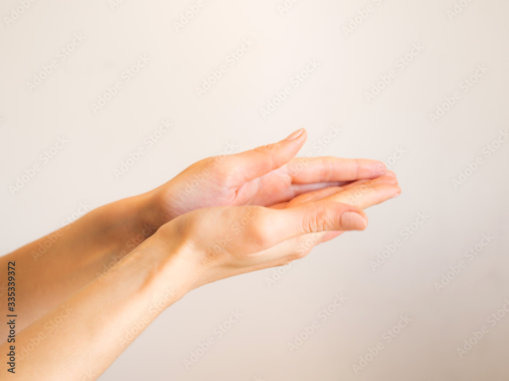 Female hands cleaning washing with sanitizer gel over bright gray background Female hands cleaning washing with sanitizer gel over bright gray background