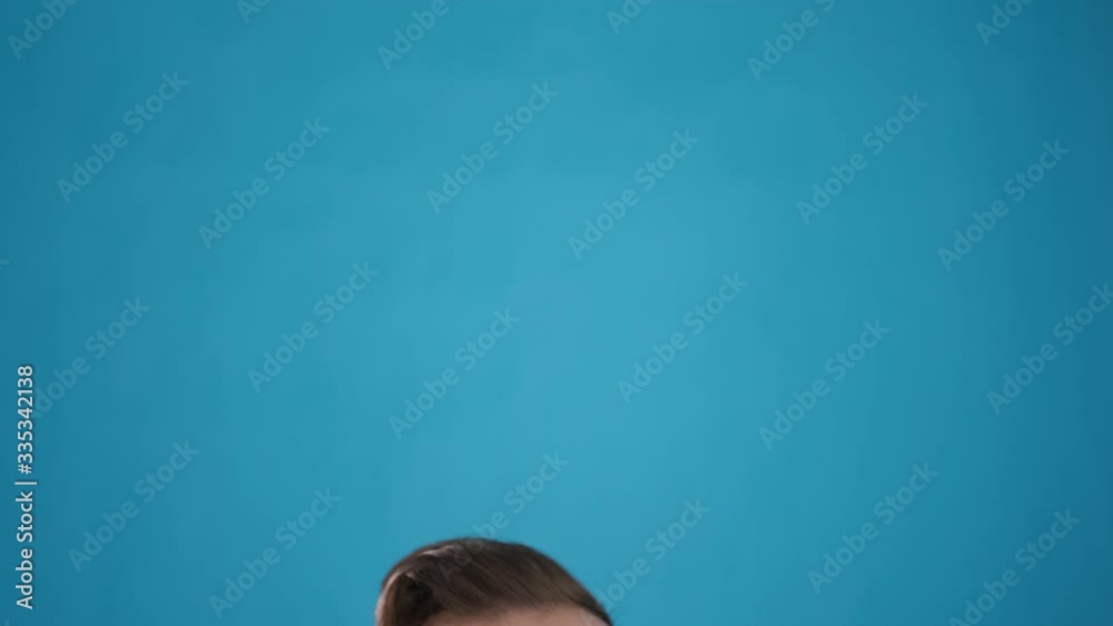 portrait of Caucasian man with beard and mustache in blue shirt looks at camera, gives a thumbs up and down cool, winks and is happy, on blue background close-up 4K frame portrait of Caucasian man with beard and mustache in blue shirt looks at camera, gives a thumbs up and down cool, winks and is happy, on blue background close-up 4K frame