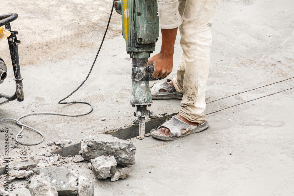 Construction worker using jackhammer drilling concrete surface