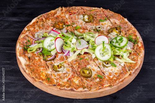 Pizza with beef mince, vegetables and cheese baked in the oven, served with salad and fresh vegetables