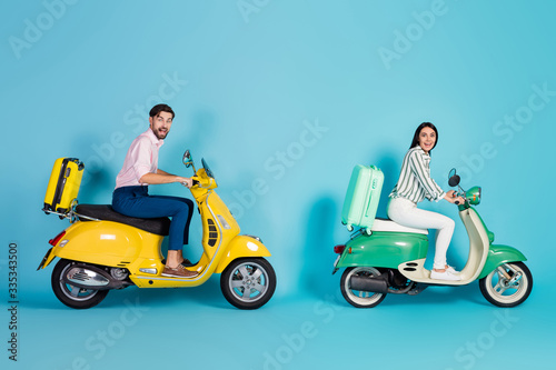 Full body profile photo of rushing excited lady guy drive two retro moped big speed rolling suitcases fixed behind addicted travelers formalwear clothes isolated blue color background © deagreez