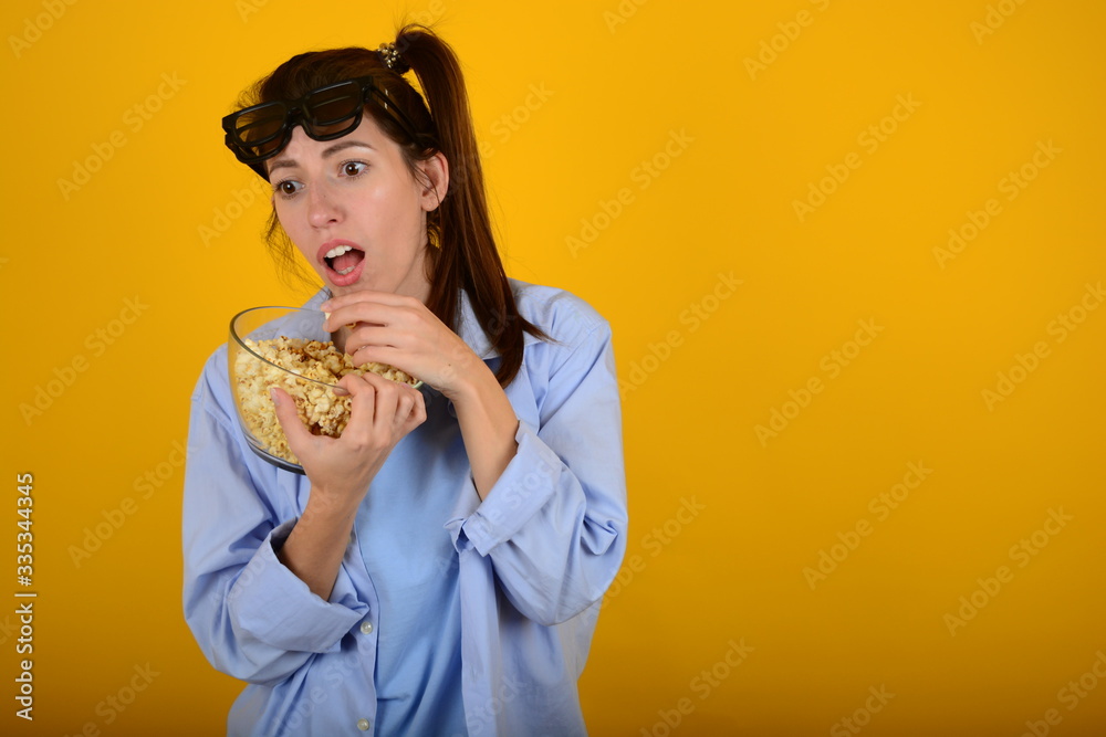 woman in 3d glasses holds a plate with popcorn in her hands