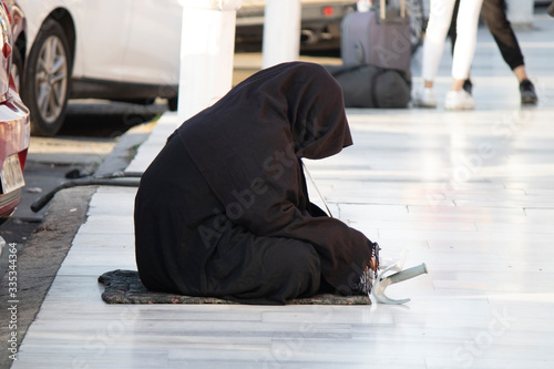 Canvas Print Woman dressed in black burka is begging on marble parquet.