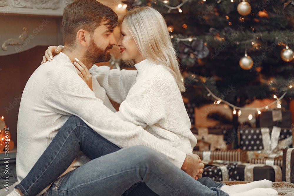 Fototapeta premium Lady in a white sweater. Family sitting on a floor. Couple near christmas tree.