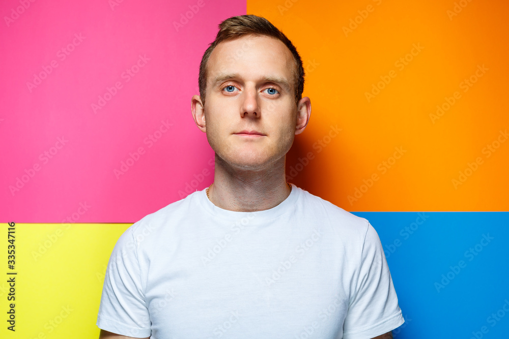 Obraz premium portrait of a young guy in a white t-shirt looking at the camera on a colored background