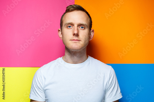 portrait of a young guy in a white t-shirt looking at the camera on a colored background