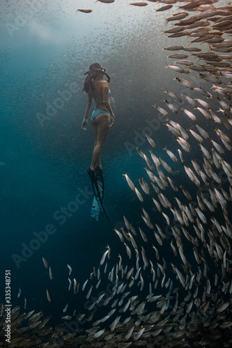 Young female free diver in a sexy swimwear ascends to the surface coming from a deep dive.