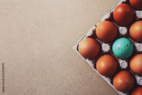 Photography one colored egg standing out amongst group of natural brown eggs, corner of cart