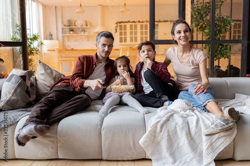 Happy family with children watching tv in living room at home. 