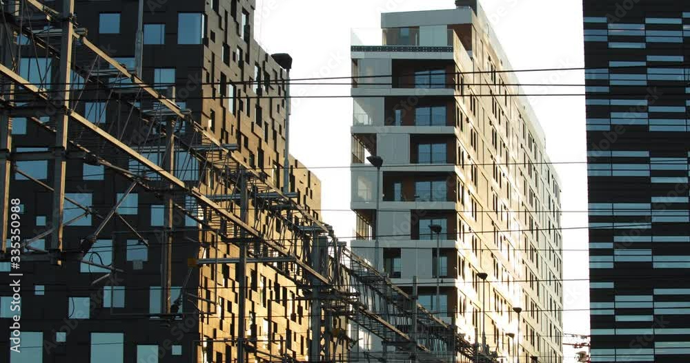 Wide parallax movement shot of residential property buildings backlit by golden February sunrise, in the modern Barcode quarter of the popular Bjørvika opera fjord district, in downtown Oslo Norway.
