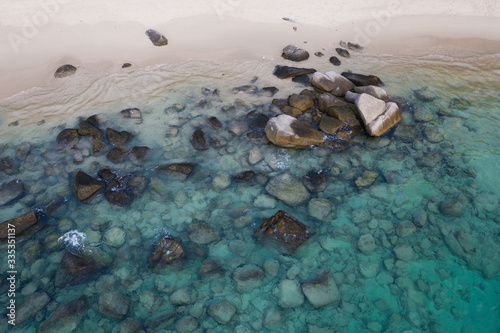Aerial drone view of crystal clear turquoise sea water and rocks