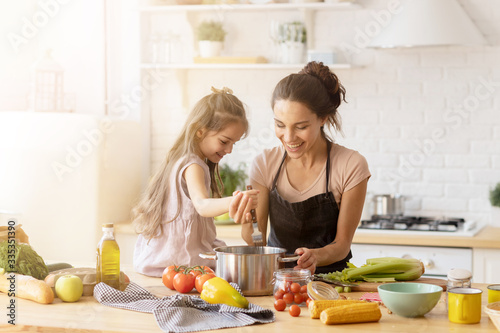 Mother and daughter preparing tasty food at kitchen.  photo