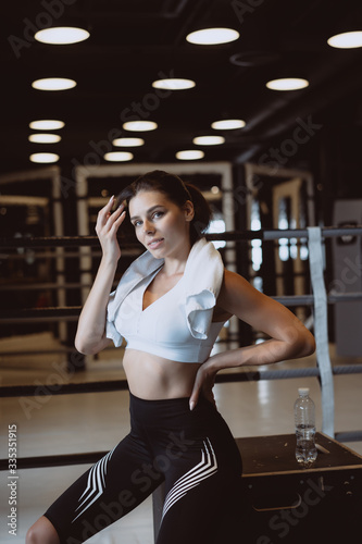 Smiling fit girl holding towel and taking rest in gym.