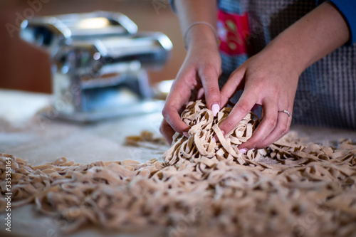 Giovane casalinga cuoca prepara la tradizionale pasta fatta in casa. Primo piano delle mani e fettuccine