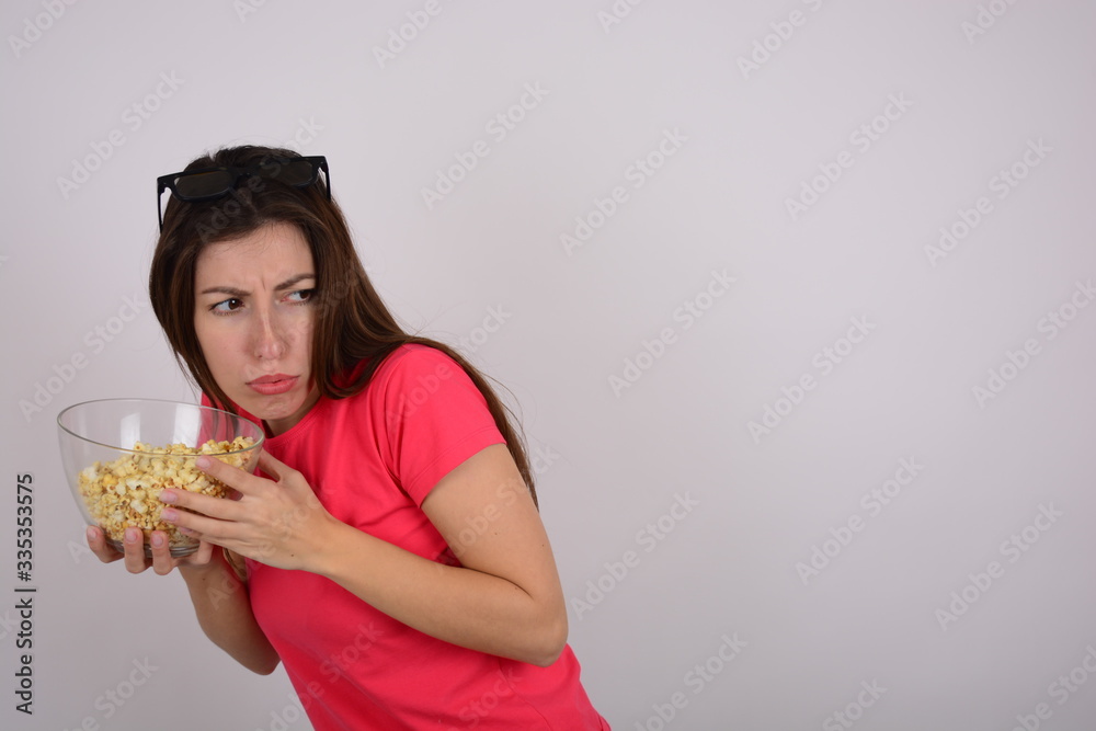 greedy woman with a plate of popcorn on a light isolated background greedy woman with a plate of popcorn on a light isolated background